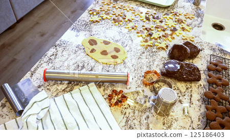 Using an adjustable rolling pin to roll out gingerbread cookie dough on the elegant marble counter in a modern kitchen, getting ready for festive holiday baking. 125186403