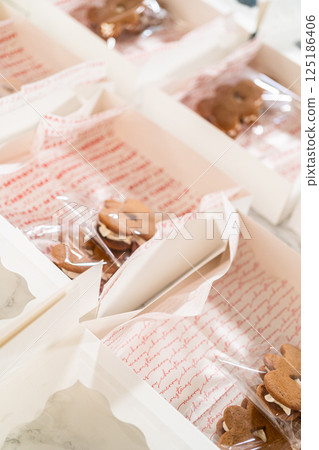 Captured from a close-up perspective, several open holiday cookie gift boxes display an assortment of decorated Christmas cookies, including gingerbread men, stars, and Christmas trees. The carefully Captured from a close-up perspective, several open holiday cookie gift boxes display an assortment of decorated Christmas cookies, including gingerbread men, stars, and Christmas trees. The carefully 125186406