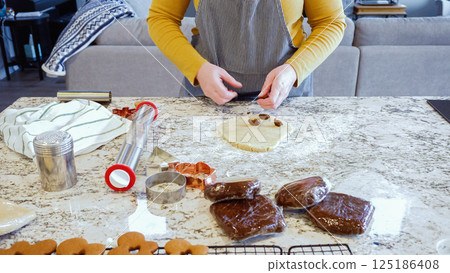 Using an adjustable rolling pin to roll out gingerbread cookie dough on the elegant marble counter in a modern kitchen, getting ready for festive holiday baking. Using an adjustable rolling pin to roll out gingerbread cookie dough on the elegant marble counter in a modern kitchen, getting ready for festive holiday baking. 125186408