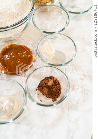A complete setup of ingredients for Gingerbread Bundt Cake With Caramel, including flour, spices, molasses, caramel, and butter, arranged for easy baking preparation. A complete setup of ingredients for Gingerbread Bundt Cake With Caramel, including flour, spices, molasses, caramel, and butter, arranged for easy baking preparation. 125186413