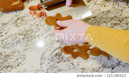 Using various festive cookie cutters, we're cutting out charming gingerbread cookies from the rolled dough on the sleek marble counter, bringing holiday cheer to the modern kitchen. 125186422