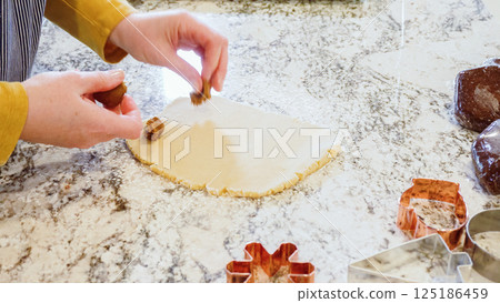 Using an adjustable rolling pin to roll out gingerbread cookie dough on the elegant marble counter in a modern kitchen, getting ready for festive holiday baking. 125186459