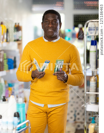 Before buying in household shop, African male customer choose toothbrush Before buying in household shop, African male customer choose toothbrush 125186463