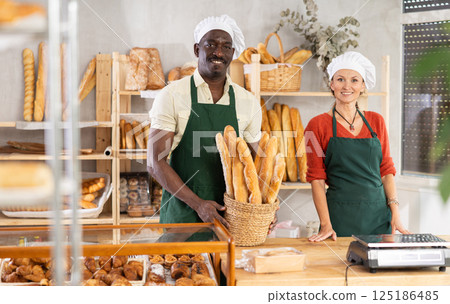Joyful male and female bakers at counter in bakery Joyful male and female bakers at counter in bakery 125186485