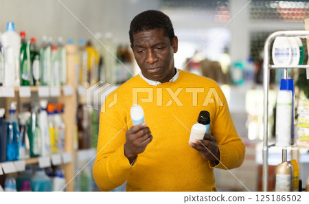 Before buying in household shop, African male customer choose roll on deodorant 125186502