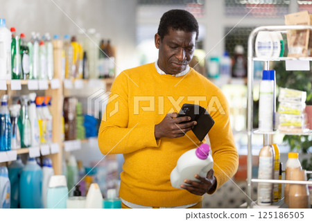 Checking expiration date of detegrent - male shopper scans QR code on label of detegrent using smartphone 125186505