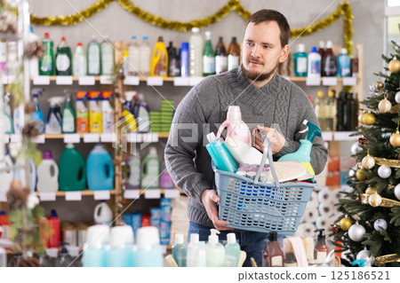 Middle-aged man with full basket choosing something in supermarket during X-mas 125186521