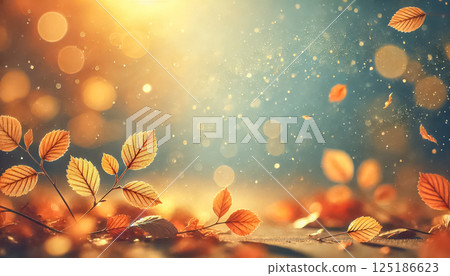 Small autumn leaves glow under warm sunlight with a highly blurred background and delicate, out-of-focus particles. The soft gradient of light blue and golden hues creates a peaceful, tranquil scene 125186623