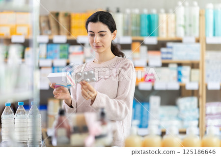 Young woman chooses pills at pharmacy 125186646