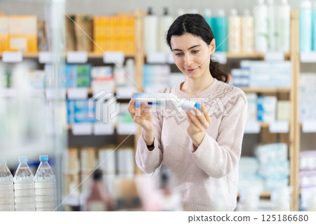Young woman chooses ointment at pharmacy 125186680