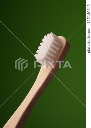 A wooden toothbrush on a green background. Oral health. Eco toothbrush. A wooden toothbrush on a green background. Oral health. Eco toothbrush. 125186843