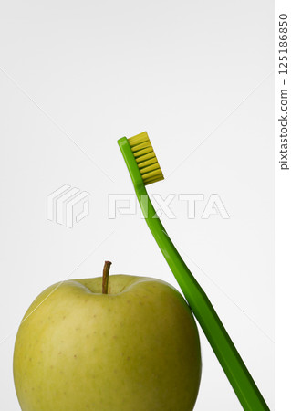 Oral hygiene with a green apple and a green toothbrush on a light gray background. Oral health. Oral hygiene with a green apple and a green toothbrush on a light gray background. Oral health. 125186850