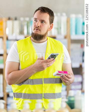Male builder scans code on package of paracetamol pills to check expiration date Male builder scans code on package of paracetamol pills to check expiration date 125186852