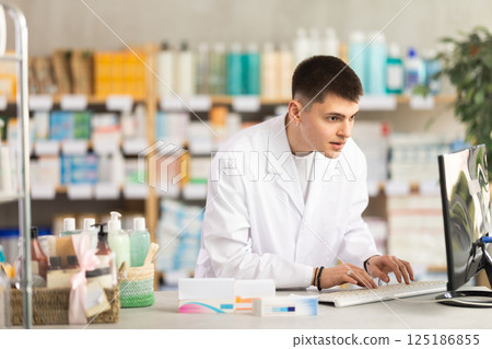 Young man pharmacist uses computer at workplace Young man pharmacist uses computer at workplace 125186855