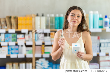 Girl buys emollient body cream at pharmacy Girl buys emollient body cream at pharmacy 125186857
