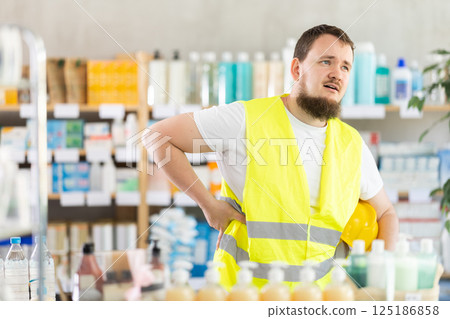 Young man builder with back pain at pharmacy 125186858