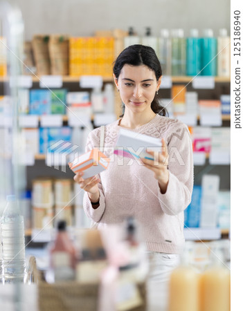 Young woman choosing boxes of pills in pharmacy 125186940