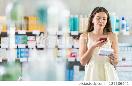 woman scans a package of pills on her phone 125186941