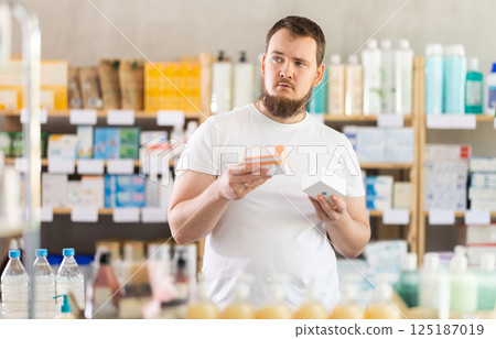 Man carefully selects pills in modern pharmacy 125187019