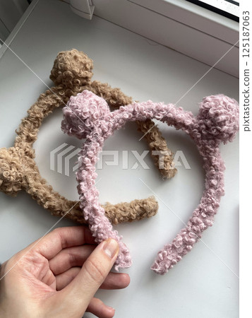 handmade headbands curly texture pink and brown color in girl's hand 125187063