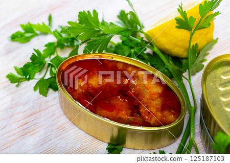 Tinned cod in tomato sauce on background with greens and lemon Tinned cod in tomato sauce on background with greens and lemon 125187103