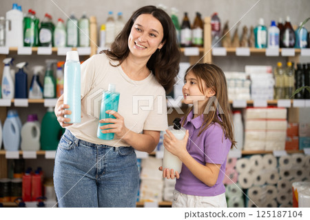 Woman with a child chooses shampoo and shower gel Woman with a child chooses shampoo and shower gel 125187104