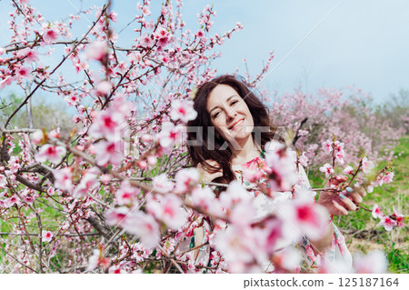 woman smiling in flower dress in spring blooming garden 125187164