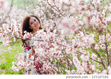 woman walking in flower dress in spring blooming garden 125187168