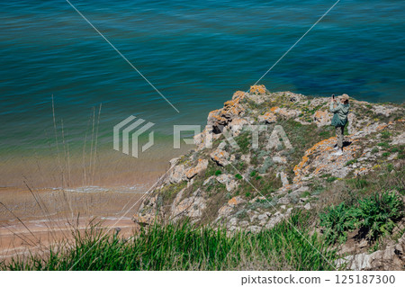 Female tourist taking photos of seascape from top of cliff Female tourist taking photos of seascape from top of cliff 125187300