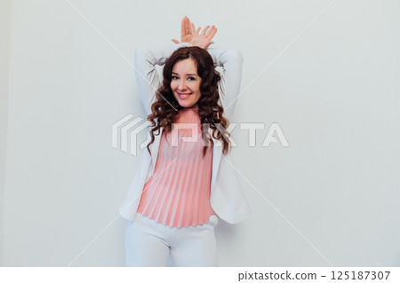 brunette woman showing her hands the ears of a hare on the white background brunette woman showing her hands the ears of a hare on the white background 125187307