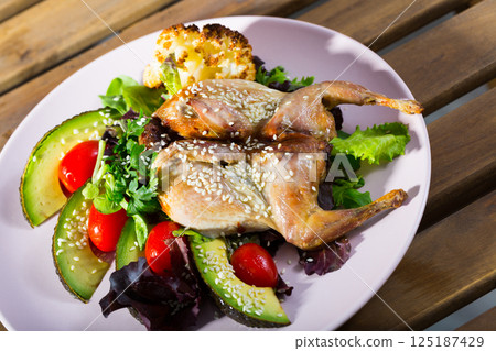 Quail-tobacco with sesame and salad of avocado is tasty dish 125187429