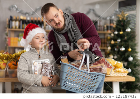 Dad and son are choosing products for New Year celebration in supermarket 125187432