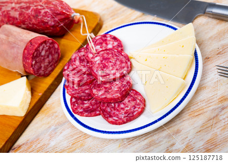 Healthy spanish snack tapas, slicing sausages and cheeses served on plate Healthy spanish snack tapas, slicing sausages and cheeses served on plate 125187718