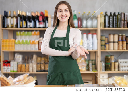 Girl stands near counter in grocery department of store, gesturing to look at assortment 125187720