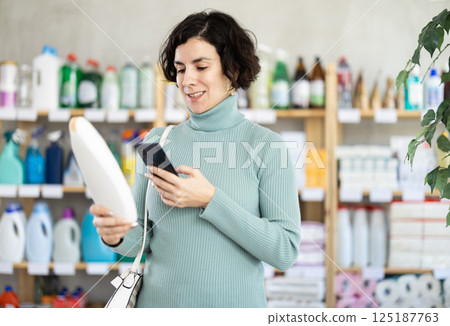 Adult woman scanning qr code for shampoo or shower gel 125187763