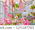 A toy poodle enjoying the flowers in the greenhouse 125187765