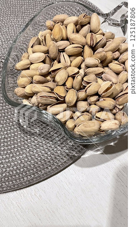 pistachios in a glass vase on a napkin on the table 125187806