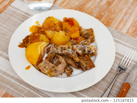 Spicy braised potatoes with pieces of rabbit on plate 125187815