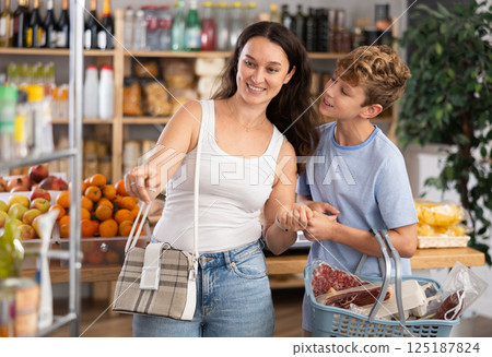 Teen boy standing with basket during shopping with mom 125187824