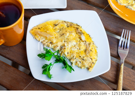 Fried omelette with chicken fillet pieces, cheese and greens Fried omelette with chicken fillet pieces, cheese and greens 125187829