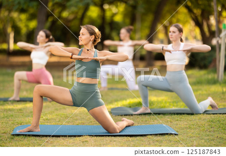 Group yoga classes in summer park - girls in different yoga poses 125187843