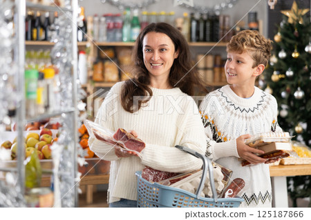 Adult woman with son choosing products in grocery store 125187866