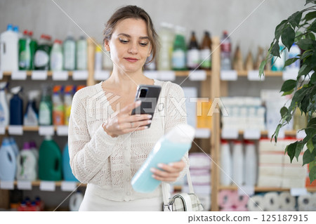 Young woman scanning qr code for shampoo or shower gel 125187915