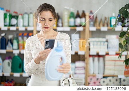 Woman client scans QR code on package and downloads promo code to purchase liquid powder 125188096