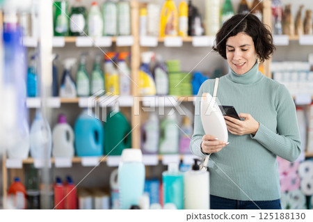 Middle-aged woman scanning QR-code on shampoo at department store 125188130