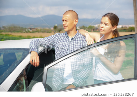 Positive elegant couple of tourists woman and man standing near car 125188267