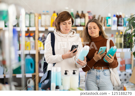 Two women scanning QR-code on shampoo in department store 125188270