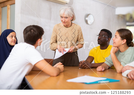 Group of multinational people discussing documents at table Group of multinational people discussing documents at table 125188293