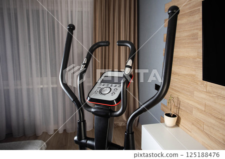 New modern elliptical trainer at home in the exercise room, close-up New modern elliptical trainer at home in the exercise room, close-up 125188476