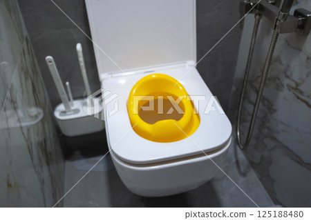 Yellow child toilet seat for children in the toilet. Convenience and comfort for the child on the toilet, close-up Yellow child toilet seat for children in the toilet. Convenience and comfort for the child on the toilet, close-up 125188480